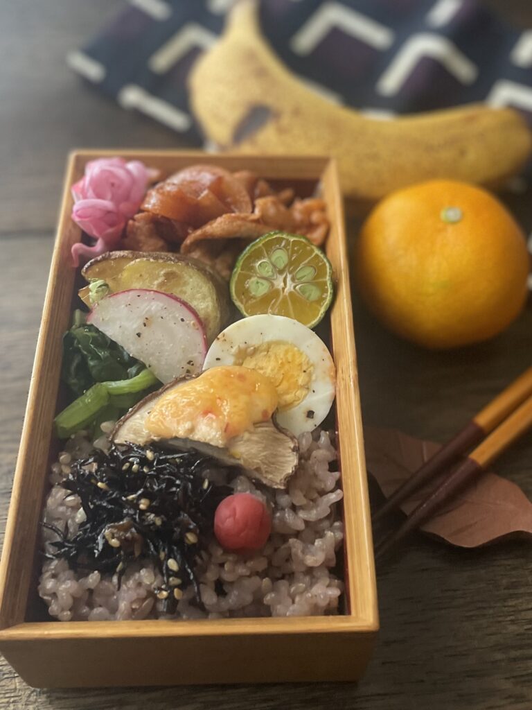 ポークチャップや焼き野菜、黒豆入り玄米を詰めた彩り豊かなお弁当の全体写真。